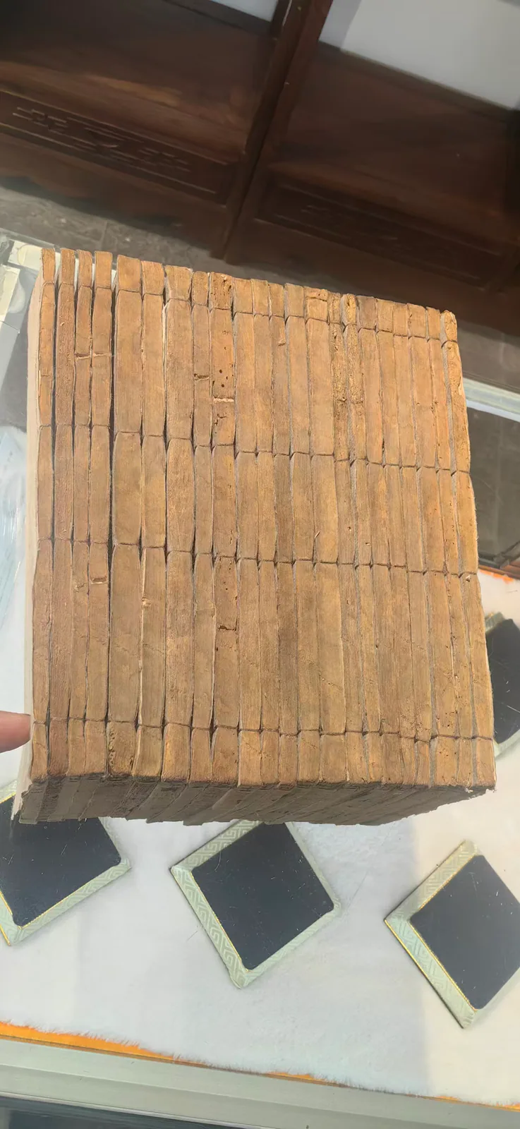 这张图片展示的是郑福兰堂珍藏版的线装多册《黄帝内经》，是两百余年的古旧中医典籍藏品，这些古籍装订为规整的一摞，册页外观呈泛黄的棕褐色，纸张带有古旧岁月留下的痕迹，部分册页表面可见细微的岁月损耗痕迹。该典籍陈列于展柜之中，是中医学重要典籍的实物留存，呼应了文档中关于《黄帝内经》为中医理论基石的内容。