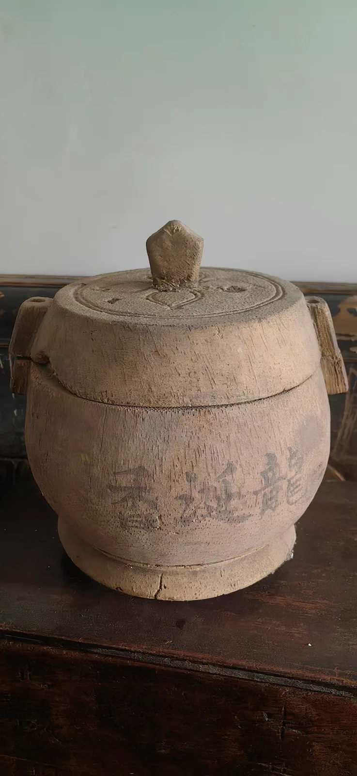 图片展示的是郑福兰堂里用于盛放龙涎香的木罐。罐体呈圆柱形，盖子扣得严实，器壁厚实，盖上有心形图案。罐身刻有“龙涎香”字样，表明其用途。木罐放置在木制桌面上，背景为浅色墙面。图片与上下文紧密相关，直观呈现了文中提到的“单放一味的‘专放’”的木罐，用于盛放龙涎香这一名贵药材，强调其专为药材收存设计，确保不混不串，稳妥存放。